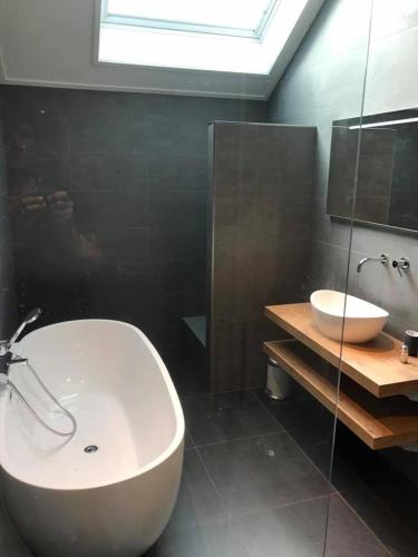 La salle de bains est pourvue d'une baignoire blanche et d'un lavabo. dans l'établissement De beurs, à Hollum