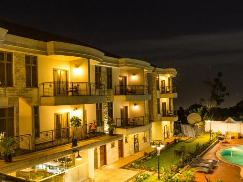 an apartment building with a swimming pool at night at Alba Hotel Meru in Meru