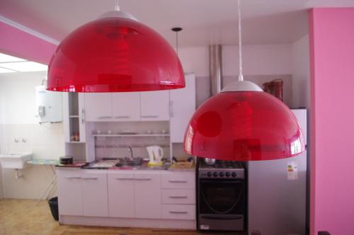 uma cozinha com dois candeeiros vermelhos pendurados no tecto em Costa Aguacates em Posadas