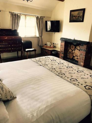 a bedroom with a large white bed with a fireplace at Slaters Country Inn in Whitmore