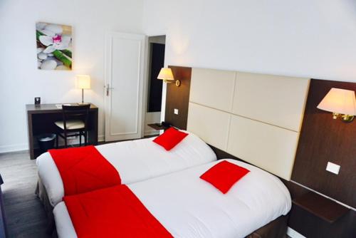 a hotel room with a bed with red pillows at Hôtel D'orsay in Orsay