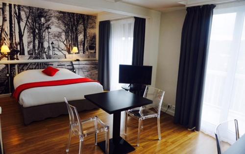 a bedroom with a bed and a table and chairs at Hôtel D'orsay in Orsay