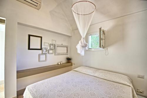 サン・ミケーレ・サレンティーノにあるIl Trullo di Laura by PosarelliVillasの白いベッドルーム(ベッド1台、窓付)