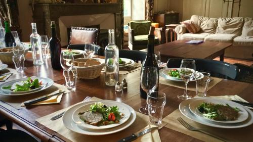 a wooden table with plates of food and wine glasses at Domaine de l'Amiral in Saint-Laurent-du-Pape