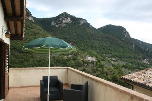 a green umbrella sitting on a balcony with a mountain at Valle del Belvedere in Spoleto