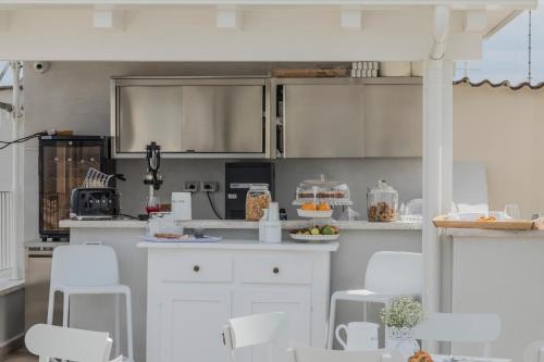 a kitchen with white cabinets and white chairs at BORGOBELTRANI in Trani