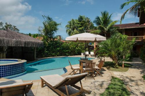 a pool with chairs and a table and an umbrella at Pousada Bico Verde in Juquei