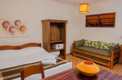 a bedroom with two beds and a couch and a table at Pousada Bico Verde in Juquei