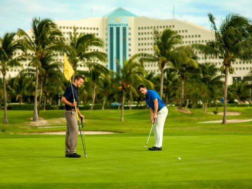 two men are playing golf on a golf course at Iberostar Selection Cancun in Cancún