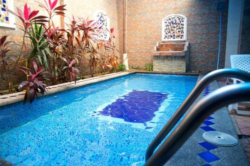 a large swimming pool with blue water and plants at Tropical Inn Hotel in Guayaquil