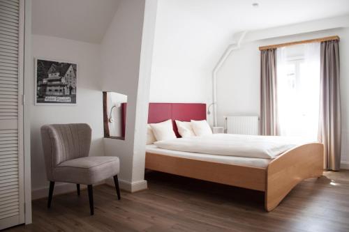 a bedroom with a large bed and a chair at Hotel Flosdorff - Appartements in Monschau