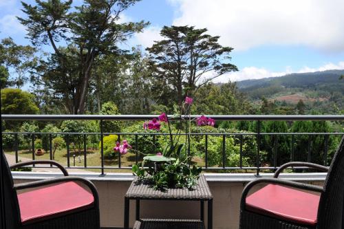 a table with a vase of flowers on a balcony at Quinta Da Cova Do Milho in Santo António da Serra