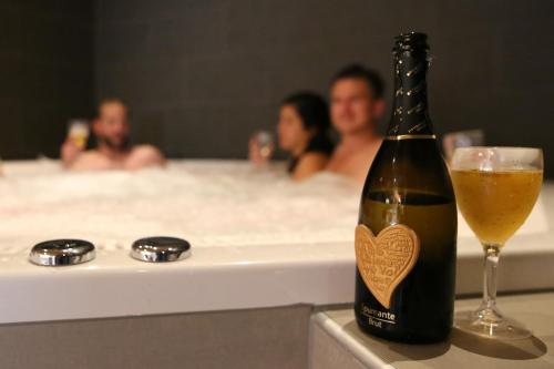 a bottle of beer and a glass of champagne in a bathtub at Karlstad Swecamp Bomstadbaden in Karlstad