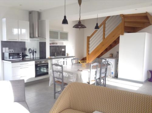 une cuisine avec des armoires blanches et une table et des chaises dans l'établissement Gite au Coeur de la Sologne, à Pruniers