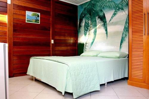um quarto com uma cama branca e um mural de palmeira em Pousada Luz do Sol em Rio das Ostras