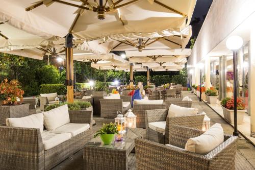 a patio with wicker chairs and tables and umbrellas at Mercure Genova San Biagio in Genova