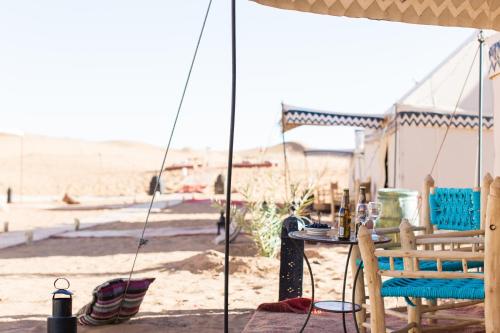 un tavolo e sedie sotto una tenda sulla spiaggia di Desert Luxury Camp a Merzouga