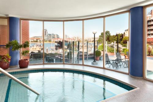a large swimming pool in a building with windows at Coast Victoria Hotel & Marina by APA in Victoria