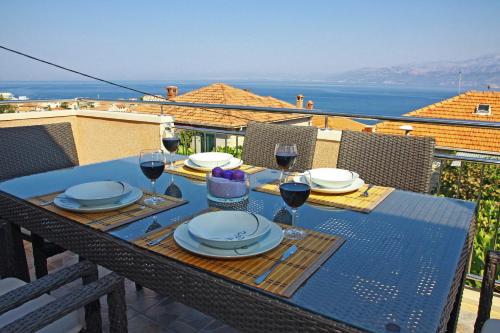 a table with plates and wine glasses on a balcony at Vacation House on island Brac - Ana in Postira