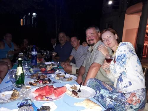 a group of people sitting around a table with food at Merabi Guest House in Makhinjauri
