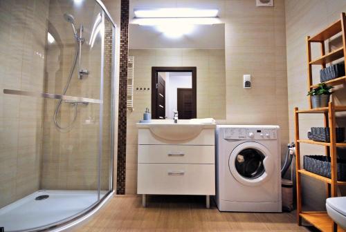 uma casa de banho com um chuveiro e uma máquina de lavar roupa em Polanki Sea Kolberg em Kolobrzeg