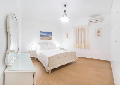 a white bedroom with a bed and a mirror at New Mykonos town house in Mýkonos City