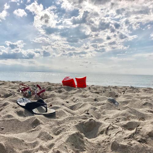 a pair of flip flops and a surfboard on the beach at Ferienhof Utech in Wenkendorf auf Fehmarn