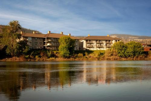 a large apartment building next to a body of water at Riverland Inn & Suites in Kamloops