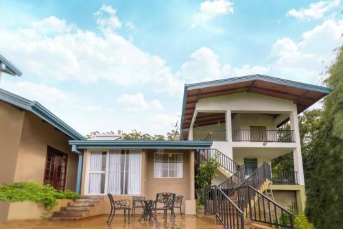 a house with a balcony with tables and chairs at Villa Lemon Court in Nuwara Eliya