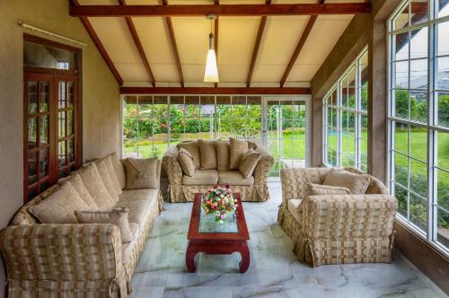 a screened in porch with couches and a table at Villa Lemon Court in Nuwara Eliya
