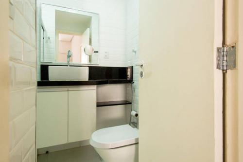 een witte badkamer met een toilet en een spiegel bij Copacabana Frente para a Praia 1005 in Rio de Janeiro