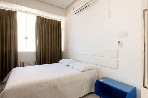 een slaapkamer met een wit bed en een blauwe kruk bij Copacabana Frente para a Praia 1005 in Rio de Janeiro