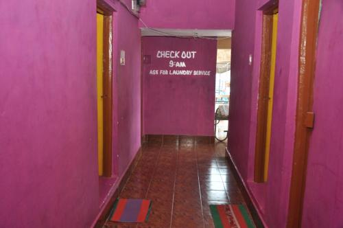 a hallway with a pink wall with a sign on it at Vicky's Home Stay Hampi in Hampi