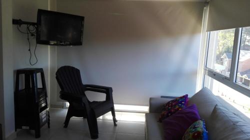 sala de estar con sofá, silla y TV en Besugo en Pinamar