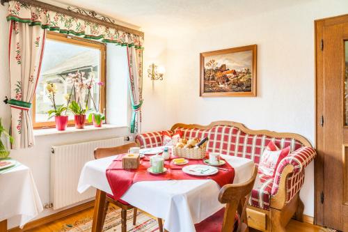 a dining room with a table and a red and white couch at Waschlgut in Ebenau