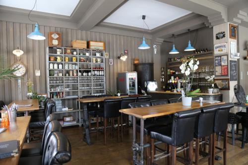 un bar con mesas de madera y sillas negras en L'Hotel De France, en Roubaix