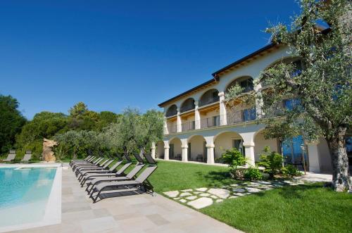 uma villa com uma piscina e espreguiçadeiras em Ca' Barbini Resort em Garda