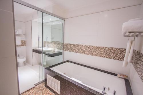 a bathroom with a tub and a toilet and a sink at Carnaval Hotel Casino in Encarnación