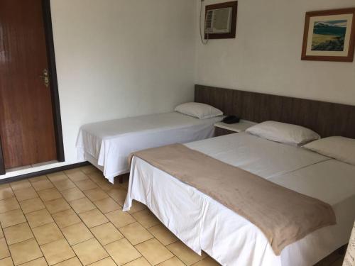 a room with two beds and a tiled floor at Hotel Luz do Sol in Balneário Camboriú