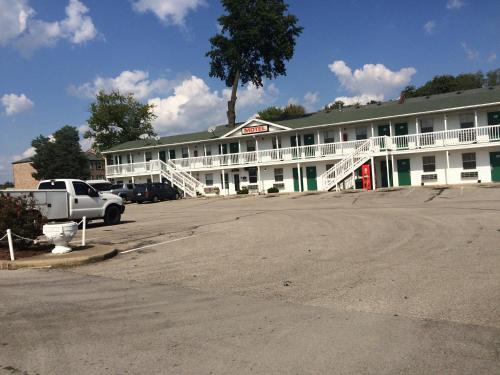 a white building with a parking lot in front of it at Hoosier Travel Lodge in Jeffersonville