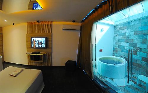 a bathroom with a tub and a tv in a room at Eros Hotel CDU (Adults Only) in Recife