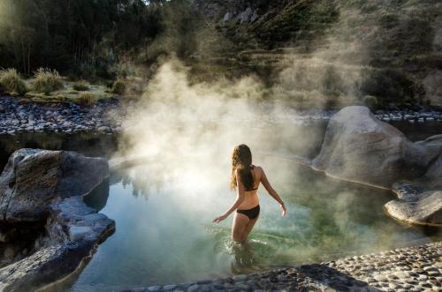 a woman in a bathing suit standing in a body of water at Colca Lodge Spa & Hot Springs in Yanque