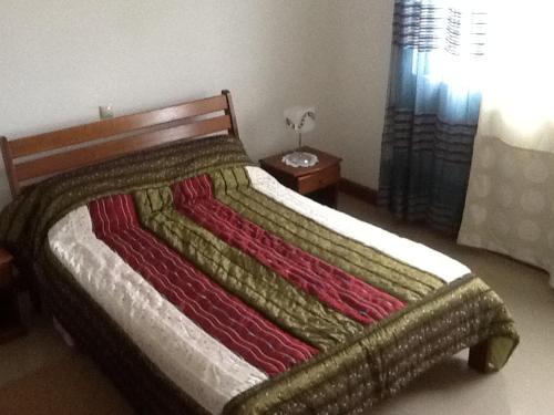 Un dormitorio con una cama con una manta de colores. en E Gravana, en São Tomé