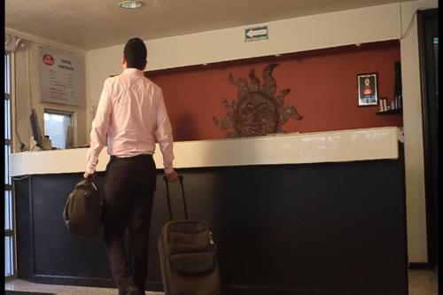 un homme avec une valise debout à un comptoir dans l'établissement Hotel Flamingo, à Ciudad Juárez