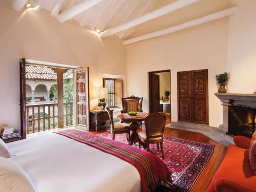 1 dormitorio con cama, mesa y chimenea en Inkaterra La Casona Relais & Chateaux en Cusco