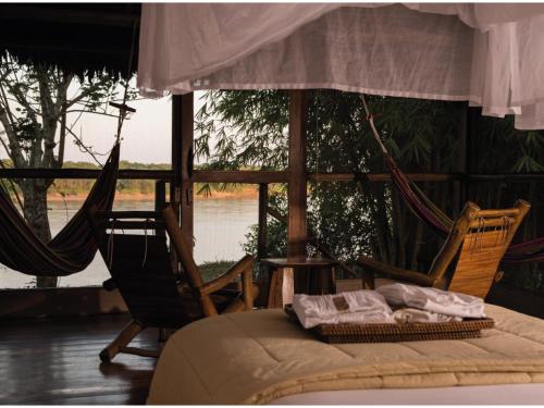 a bedroom with two chairs and a bed and a window at Inkaterra Reserva Amazonica in Puerto Maldonado