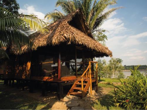 a small hut with a thatched roof and a palm tree at Inkaterra Reserva Amazonica in Puerto Maldonado