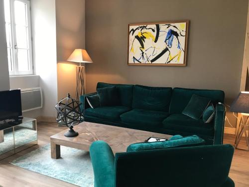 a living room with a green couch and a table at Les Maisons du Périgord in Terrasson-Lavilledieu