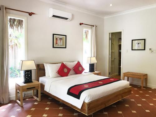 a bedroom with a large bed with red pillows at Peppercorn Beach Resort in Phú Quốc