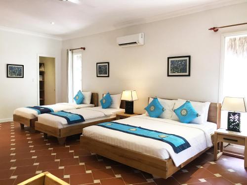 two beds in a room with blue pillows at Peppercorn Beach Resort in Phu Quoc